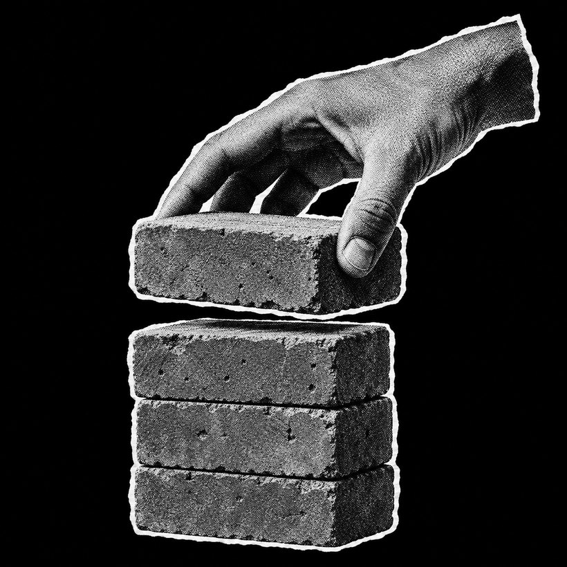 a hand placing a brick on a stack